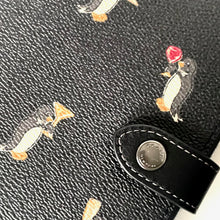 Load image into Gallery viewer, Close-up of a black leather product with penguin pattern and button detail
