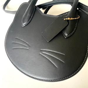 Black cat-shaped handbag with a tag on a white background