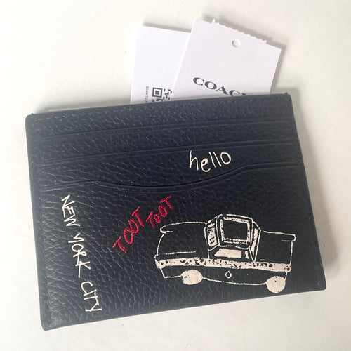 Black cardholder with 'New York City' and 'hello' text, featuring a taxi illustration, on a white background.
