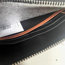 Load image into Gallery viewer, Close-up of a black leather bag with brown stitching and a visible brand label.