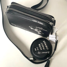 Load image into Gallery viewer, Black leather bag with &#39;New York&#39; and &#39;Coach&#39; branding on a reflective surface.