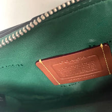 Load image into Gallery viewer, Close-up of a brown leather tag on a green fabric surface with visible stitching.