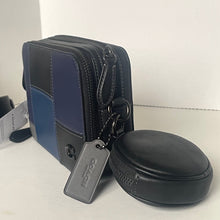 Load image into Gallery viewer, Blue and black zippered pouch with a round black case and tag on a light surface.