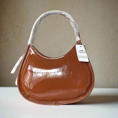 Brown handbag with a visible brand tag on a white background