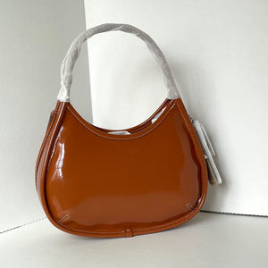 Brown handbag with a white strap on a light gray background