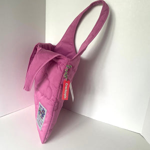 Pink quilted handbag with a visible brand tag on a white background