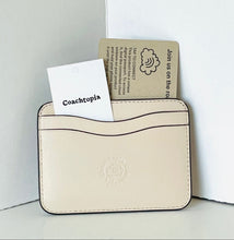 Load image into Gallery viewer, Beige cardholder with Coachtopia card and packaging on a white background
