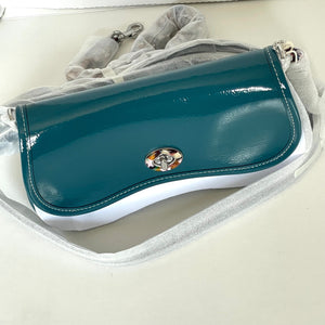Teal handbag with a silver clasp on a white surface