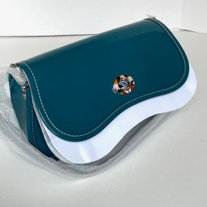 Teal handbag with a decorative button on a white background