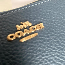 Load image into Gallery viewer, Close-up of a Coach logo on a blue leather product
