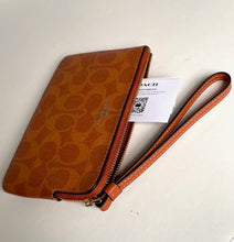 Load image into Gallery viewer, Brown Coach wristlet with a visible tag on a white background