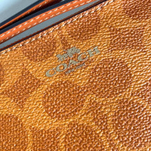 Load image into Gallery viewer, Close-up of a brown leather Coach wallet with the brand logo.