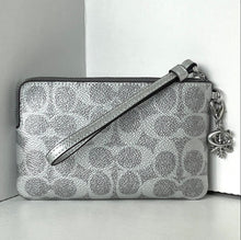Load image into Gallery viewer, Silver patterned clutch bag with a strap and charm on a light gray background