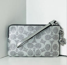 Load image into Gallery viewer, Silver patterned clutch bag with a strap and decorative charm on a light gray background