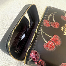 Load image into Gallery viewer, Black handbag with gold zipper and red floral embroidery on a textured surface