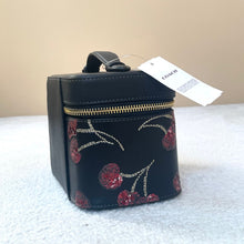 Load image into Gallery viewer, Small black handbag with floral embroidery and Coach tag on a textured surface.