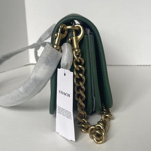 Green Coach handbag with gold chain strap on a white background