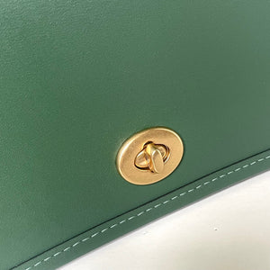 Green leather bag with a gold clasp on a white background