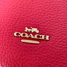 Load image into Gallery viewer, Close-up of a Coach logo on a red leather product