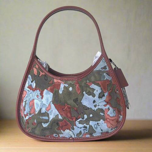 Camouflage-patterned handbag with red accents on a white background