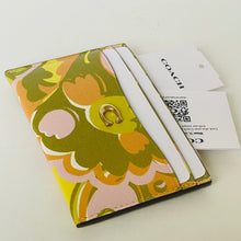Load image into Gallery viewer, Floral patterned cardholder with white handles on a light background, featuring a Coach tag.