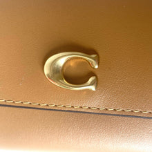 Load image into Gallery viewer, Gold horseshoe charm on a brown leather surface