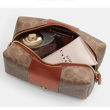 Load image into Gallery viewer, Open brown and beige toiletry bag with cosmetic items on a white background