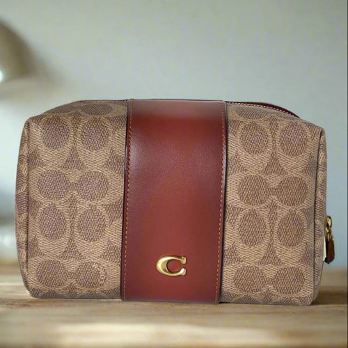 Coach handbag with brown leather stripe and logo on a white background