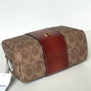 Coach handbag with brown leather strap on a white background