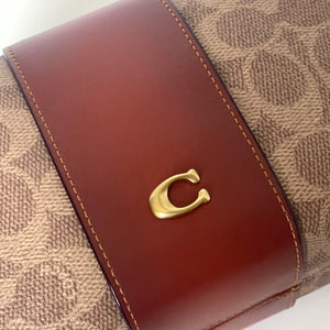 Brown leather wallet with gold logo on a beige textured background