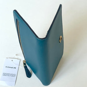 Blue leather wallet with gold accents on a white background, featuring a Coach tag.