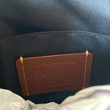 Load image into Gallery viewer, Brown leather tag with 'Coach' branding on a dark fabric background
