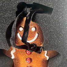 Load image into Gallery viewer, Gingerbread man ornament with a black hat on a glittery gray background