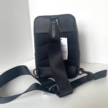 Load image into Gallery viewer, Black backpack with a visible brand tag on a white background