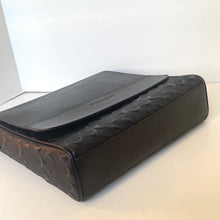 Load image into Gallery viewer, Black textured clutch bag on a light surface with a white background