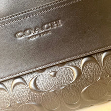 Load image into Gallery viewer, Close-up of a Coach wallet with embossed logo and branding.
