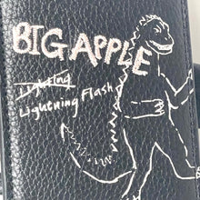 Load image into Gallery viewer, Black leather wallet with white text and graphics, including 'BIG APPLE' and a dinosaur illustration.