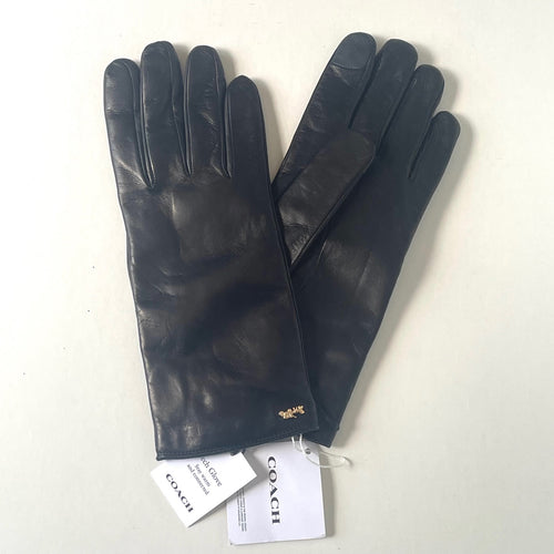 Pair of black leather gloves with Coach tags on a white background