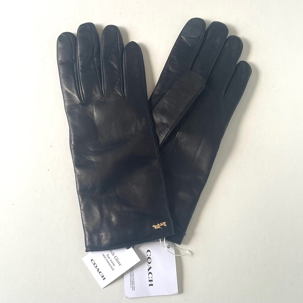 Pair of black leather gloves with Coach tags on a white background