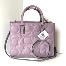 Load image into Gallery viewer, Purple handbag with a brand tag on a white background
