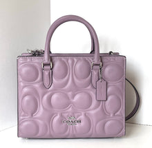 Load image into Gallery viewer, Purple Coach handbag with embossed logo on a white background