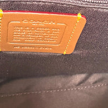 Load image into Gallery viewer, Close-up of a Coach logo on a black bag with a brown leather tag.