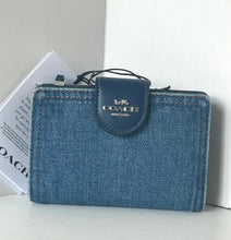 Load image into Gallery viewer, Blue denim wallet with Coach logo on a light gray surface