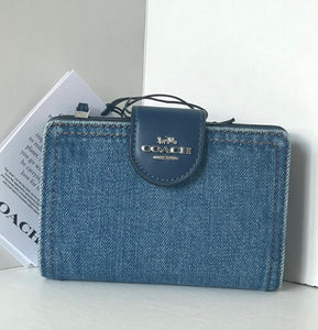 Blue denim wallet with Coach logo on a light gray surface