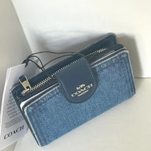 Load image into Gallery viewer, Blue Coach wallet on a white surface with a Coach magazine underneath