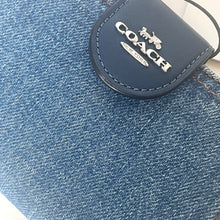 Load image into Gallery viewer, Close-up of a Coach logo on a denim surface