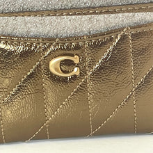 Load image into Gallery viewer, Close-up of a gold quilted handbag with a brand logo.