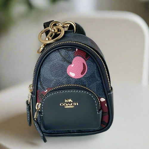 Navy blue Coach keychain bag with pink cherry design on a white background