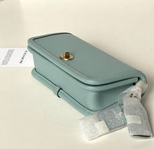 Load image into Gallery viewer, Light blue handbag with a gold clasp on a white background