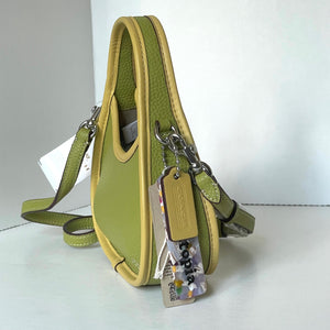 coach mini Green leather handbag with a tag on a white surface